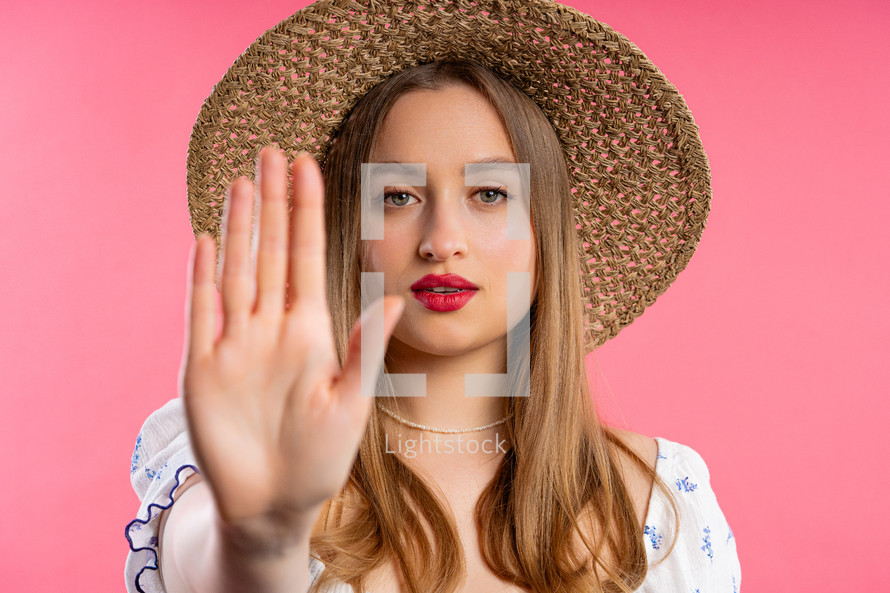 Uninterested lady disapproving with NO hand sign gesture. Denying, rejecting, disagree. Portrait of young woman on pink background, timeout concept. High quality