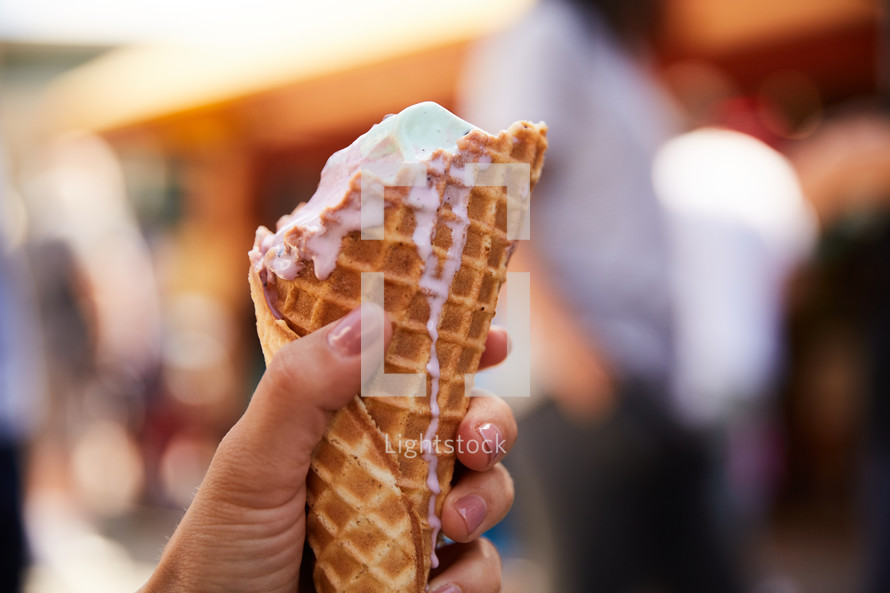 a woman holding a melting ice cream cone 