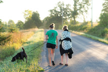 women walking a dog down a country road 