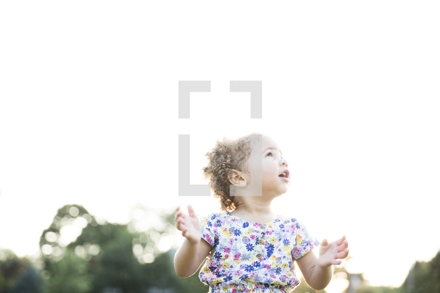 toddler girl outdoors with raised hands 