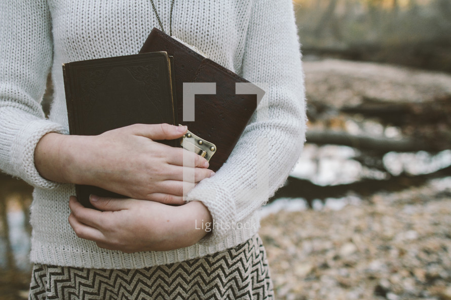 woman holding a Bible and journal to her chest 