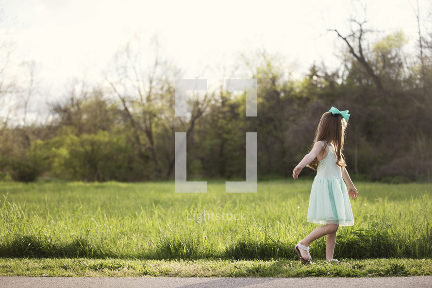 little girl in a dress walking in grass 