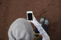 A woman in a winter hat looks at her cell phone.