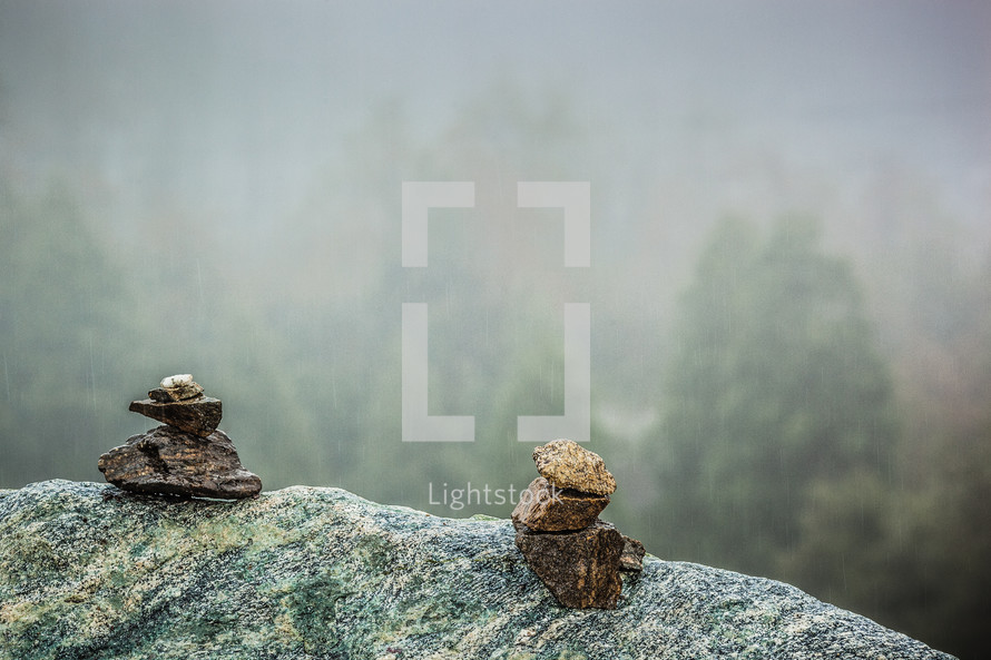 Two stacks of stones on the edge of a cliff.