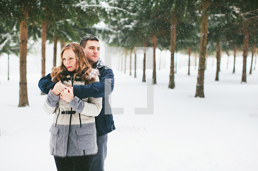 a couple standing in falling snow 