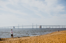 man fishing and view of a bridge from a shore 