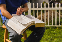 boy reading a Bible outdoors 