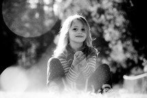 A smiling little girl sitting in sunshine.