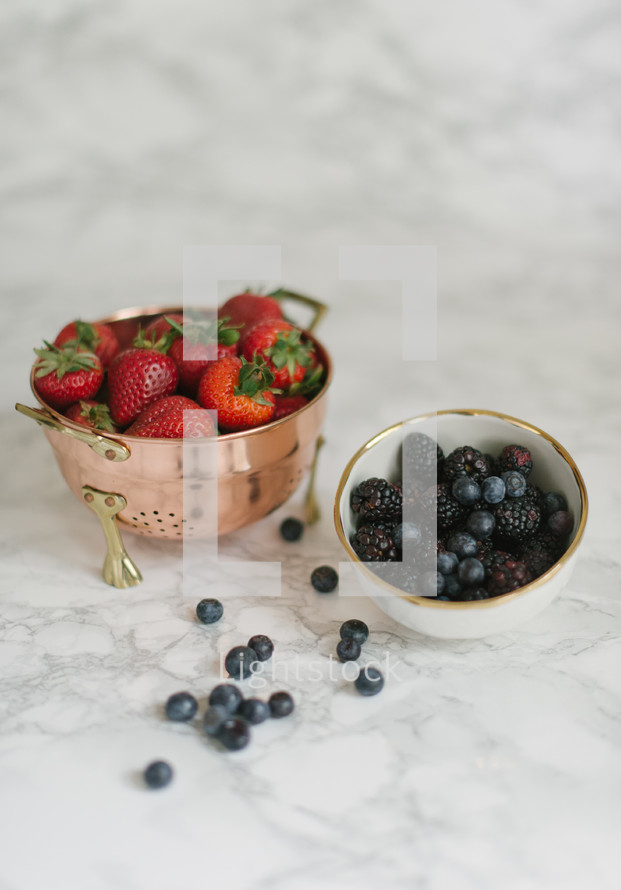 Bowls of berries on a white table.