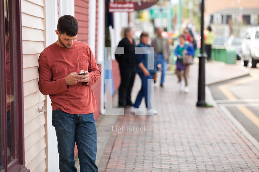 man texting on his phone standing on a sidewalk 