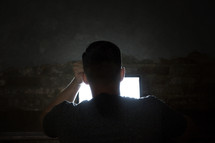 man looking at a computer screen in darkness 