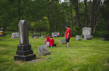 children visiting a cemetery with their father 