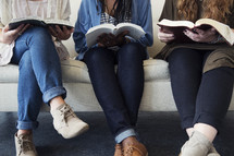 young women sitting on a couch talking, laughing, and reading bibles.