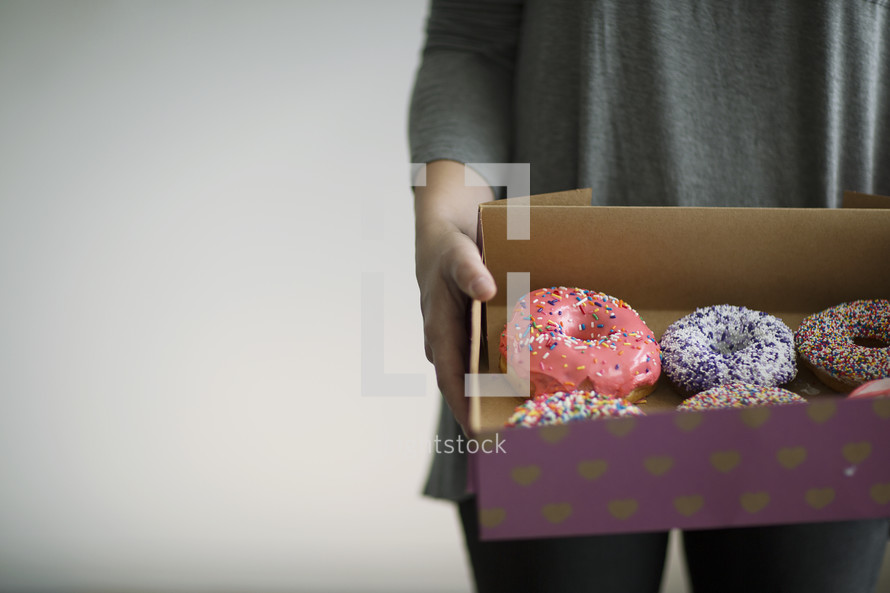 a woman holding a box of donuts