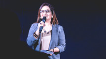 a woman holding a Bible and a microphone 