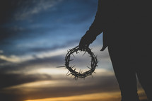 silhouette of a man holding a crown of thorns at sunset 