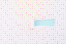 torn polka dot paper revealing blue underneath 