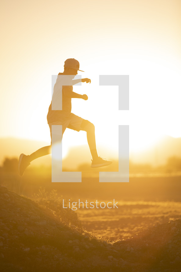 teen boy jumping in warm sunlight 