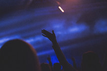 silhouettes of raised hands in an audience 