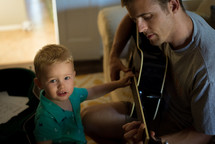 a father and son playing a guitar together 