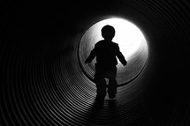child walking through a pipe tunnel