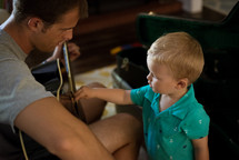 father and toddler son playing a guitar 