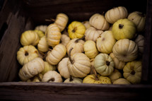 A bunch of white gourds in an old wooden box.