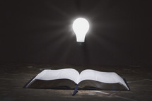 glowing lightbulb and an open Bible