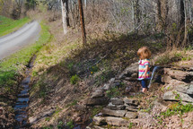 a little girl standing in a stream 