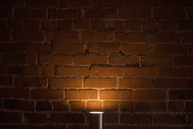 lamp glowing against a brick wall 