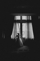 A bride poses in front of a window