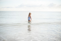 girl child in a bathing suit standing in water