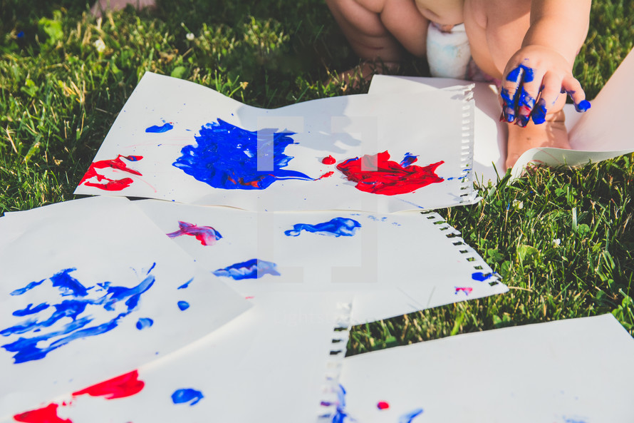 a toddler finger painting in the grass