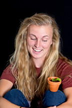 woman looking at a pot and plant on her knee 