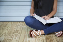 a woman sitting on a floor reading a Bible 