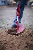 man drilling a hole in soil 