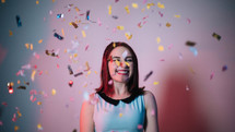 a woman standing under falling confetti 