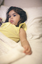 a toddler girl lying in bed 