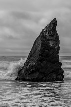A rock monolith sticking out of the ocean.