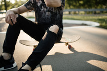 teen boy sitting on a skateboard 