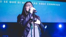 woman holding microphones singing during a worship service 