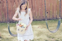 A little girl searching for eggs in a backyard Easter egg hunt 
