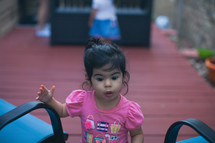 a toddler girl on a back deck 