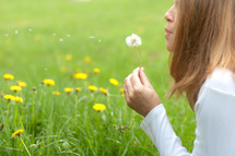 woman blowing a dandelion 