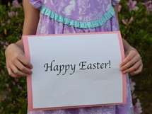 A little girl holding a Happy Easter sign 