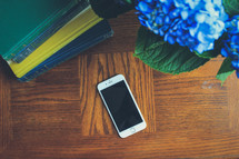 hydrangea flowers, stack of books, and cellphone on a wood table 