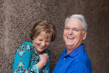 Couple, laughing, standing in front of a stone wall