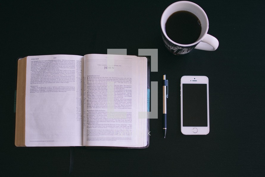 open Bible, coffee mug, pen, and cellphone 