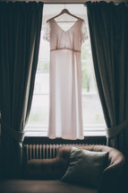 a wedding dress hanging in a window 