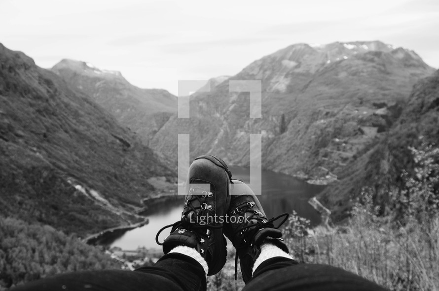 feet in boots hanging over a mountainside 